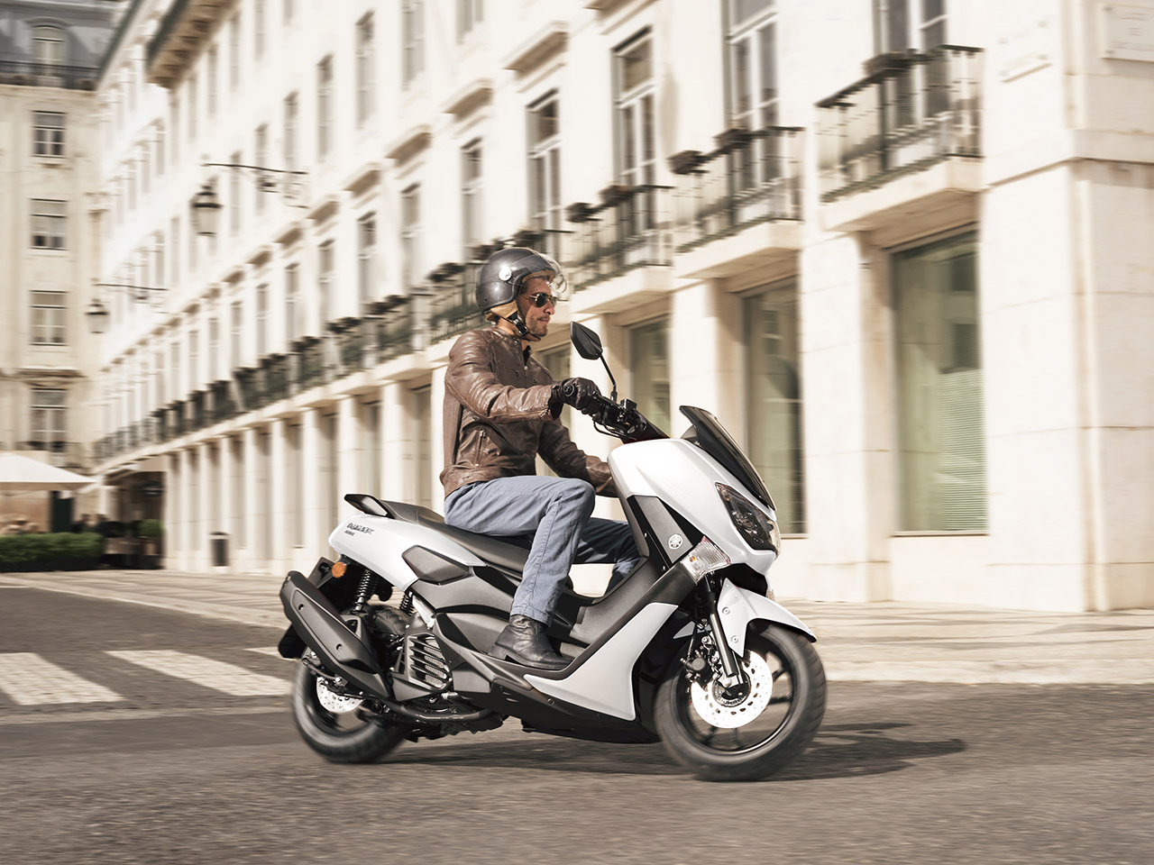 Yamaha NMAX 155 scooter in Milky white riding down city street